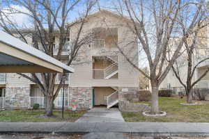 View of front facade with stone siding and a front lawn