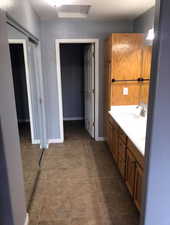 Bathroom featuring double vanity and dark tile patterned flooring