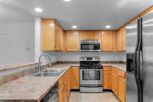 Kitchen with stainless steel appliances, recessed lighting, a peninsula, light countertops, and light tile patterned floors