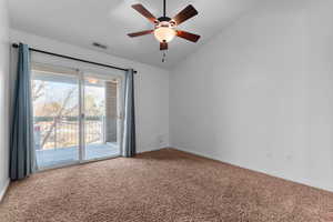 Carpeted spare room featuring vaulted ceiling and a ceiling fan