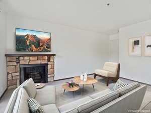 Carpeted living room with a stone fireplace and baseboards