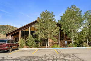 View of front facade featuring stone siding, uncovered parking, and a chimney