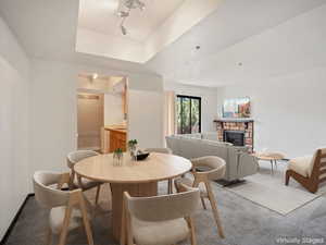 Carpeted dining space featuring a fireplace, a tray ceiling, and rail lighting