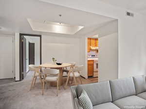 Dining space with light colored carpet and a raised ceiling