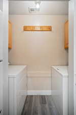 Laundry area featuring cabinet space, independent washer and dryer, and dark wood-style flooring