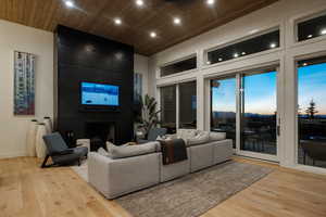 Living area featuring light wood-style flooring, a large fireplace, wooden ceiling, and recessed lighting