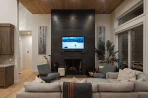 Living room with wood ceiling, light wood-style flooring, and a fireplace