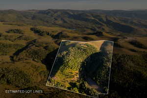 Aerial overview of property's location with property boundaries highlighted and a mountainous background