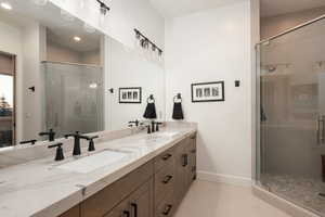 Bathroom with double vanity, a shower stall, light tile patterned flooring, and recessed lighting