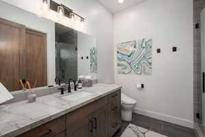 Bathroom with vanity, a shower stall, and wood finish floors