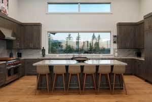 Kitchen with tasteful backsplash, a kitchen bar, dark brown cabinets, a high ceiling, and double oven range