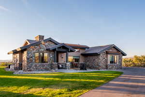 View of front of home with stone siding, a front yard, and a chimney