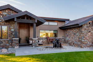 Entrance to property featuring stone siding and a lawn
