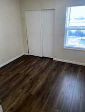 Unfurnished bedroom featuring dark wood-style floors and a closet