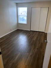 Unfurnished bedroom with a textured ceiling, dark wood-style floors, and a closet