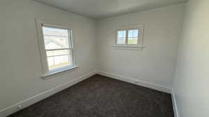 Spare room with dark colored carpet and baseboards
