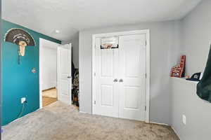 Carpeted bedroom with a closet and a textured ceiling