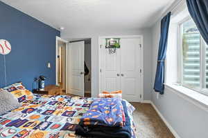 Bedroom featuring carpet flooring, a closet, and a textured ceiling