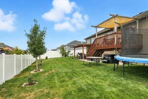 Fenced backyard featuring a trampoline, stairway, a patio area, and a wooden deck