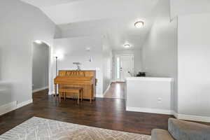 Entrance foyer featuring dark wood-style floors, lofted ceiling, and arched walkways