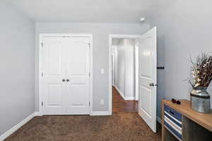 Bedroom featuring dark carpet, a closet, and a textured ceiling