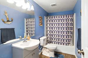 Bathroom featuring vanity, shower / bath combination with curtain, and wood finished floors