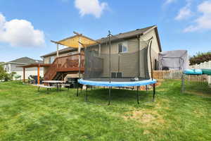 Rear view of house featuring a trampoline, a wooden deck, stairs, and a patio area