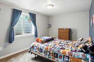 Carpeted bedroom with baseboards and a textured ceiling