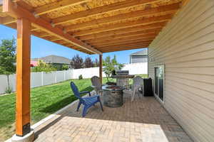 Fenced backyard with an outdoor fire pit, a patio area, and area for grilling