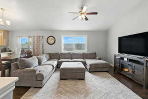 Living room with dark wood-type flooring, healthy amount of natural light, a chandelier, and ceiling fan