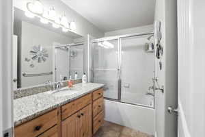 Full bath featuring shower / bath combination with glass door, vanity, light tile patterned flooring, and a textured ceiling