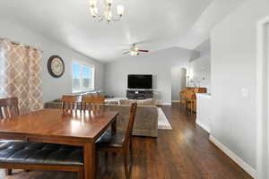 Dining room with arched walkways, vaulted ceiling, wood finished floors, a chandelier, and a ceiling fan