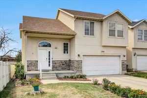View of front of property with stone siding, stucco siding, driveway, and a garage