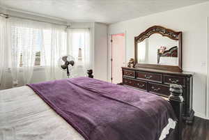 Bedroom with wood finished floors and a textured ceiling