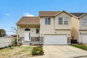 View of front of house featuring stone siding, stucco siding, and an attached garage