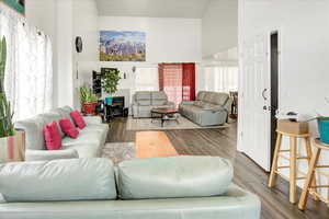 Living room featuring wood finished floors, healthy amount of natural light, and a high ceiling