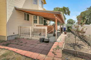 View of property exterior featuring a patio area, a fenced backyard, and a vegetable garden