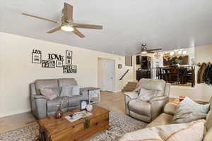 Living room with ceiling fan, wood finished floors, a textured ceiling, and a chandelier