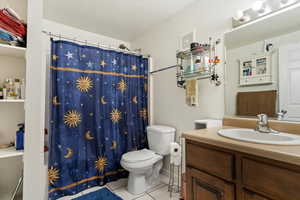 Full bathroom with light tile patterned floors, vanity, and shower / bath combo with shower curtain