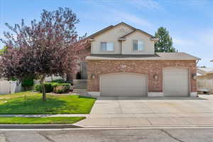 Traditional-style house featuring concrete driveway, stucco siding, an attached garage, and brick siding