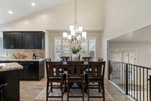 Dining area with light wood-type flooring, high vaulted ceiling, recessed lighting, and a chandelier