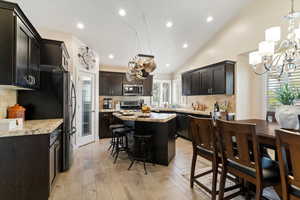Kitchen with a chandelier, tasteful backsplash, vaulted ceiling, a kitchen bar, and recessed lighting