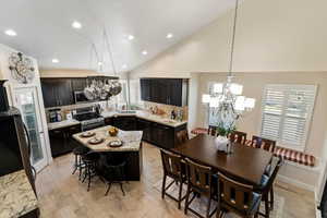 Kitchen with a chandelier, decorative backsplash, decorative light fixtures, light stone counters, and a breakfast bar
