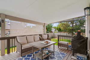 Wooden deck with an outdoor living space, a grill, and a fenced backyard