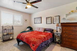 Bedroom featuring light colored carpet, ceiling fan, and a textured ceiling