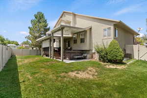 Rear view of house with a hot tub, a fenced backyard, a patio area, a gate, and stucco siding