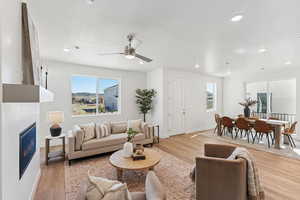 Living area featuring a glass covered fireplace, light wood finished floors, a ceiling fan, and recessed lighting