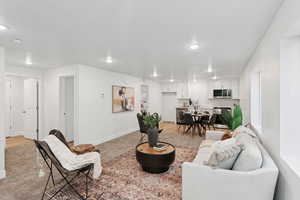 Living area with light carpet and recessed lighting