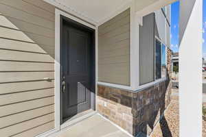 Doorway to property featuring stone siding and covered porch