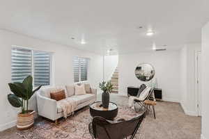 Living area with light carpet, stairway, and recessed lighting